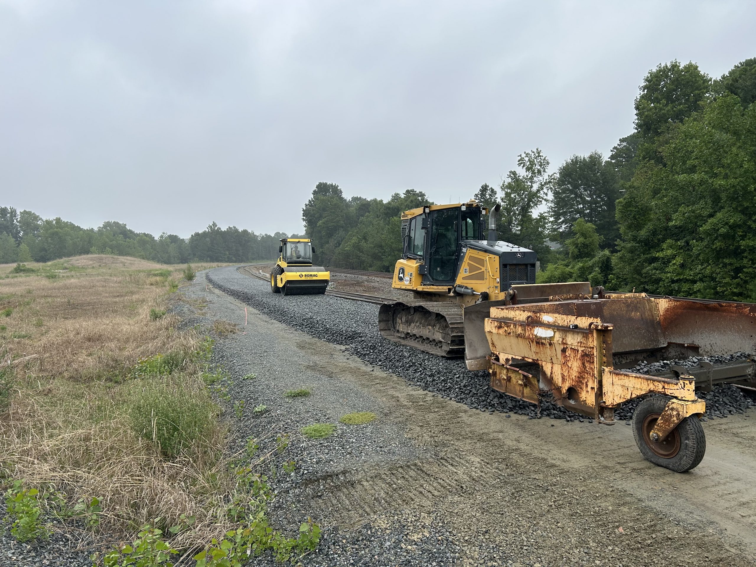 Construction equipment laying new gravel for a railroad to lie on