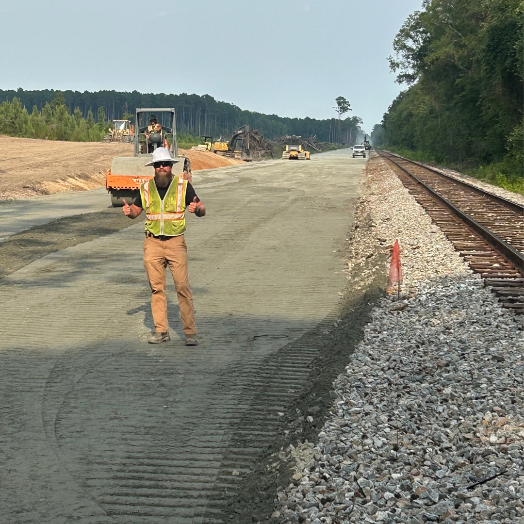A man giving a thumbs up next to a railroad track.