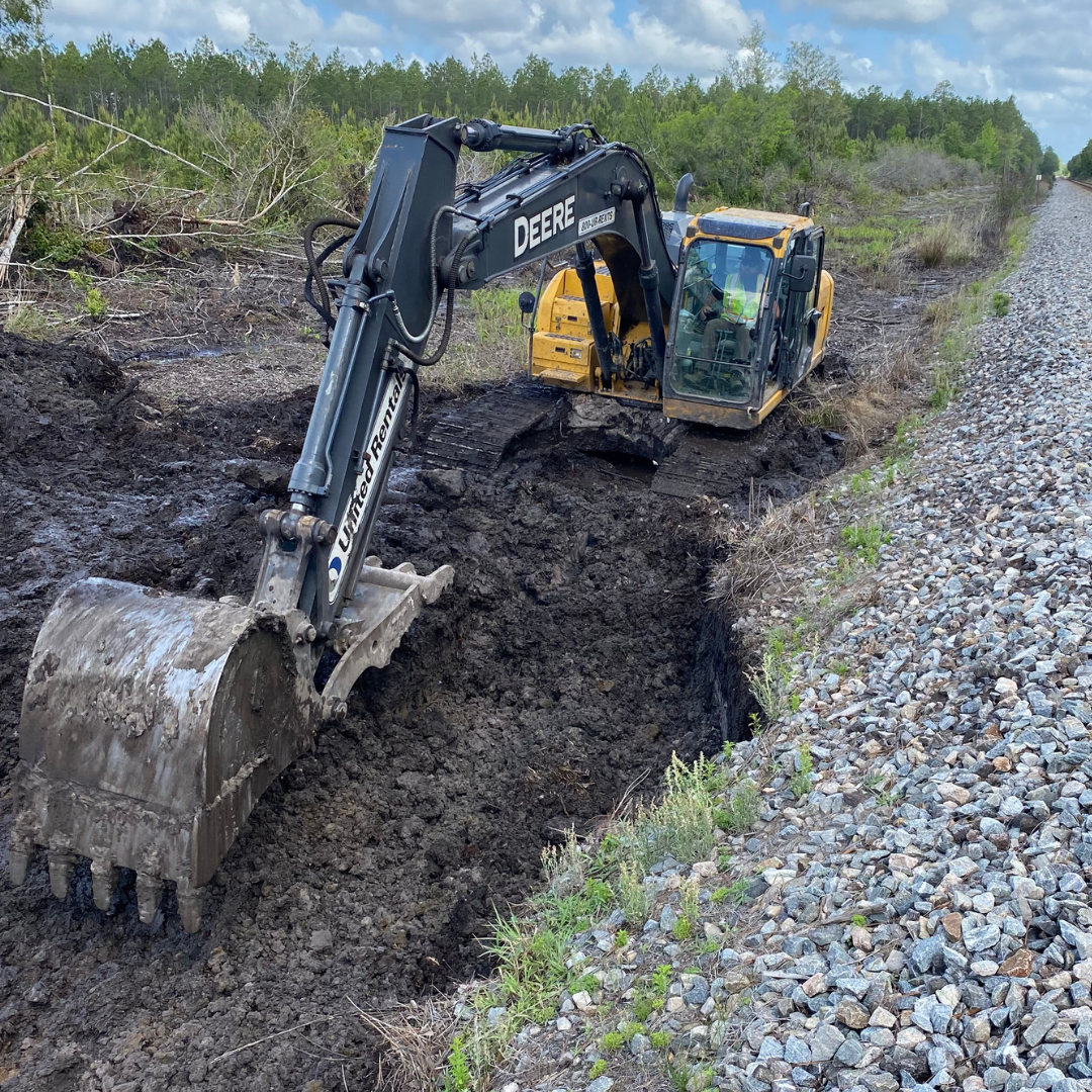 Construction machine digging the land for a new railroad track.